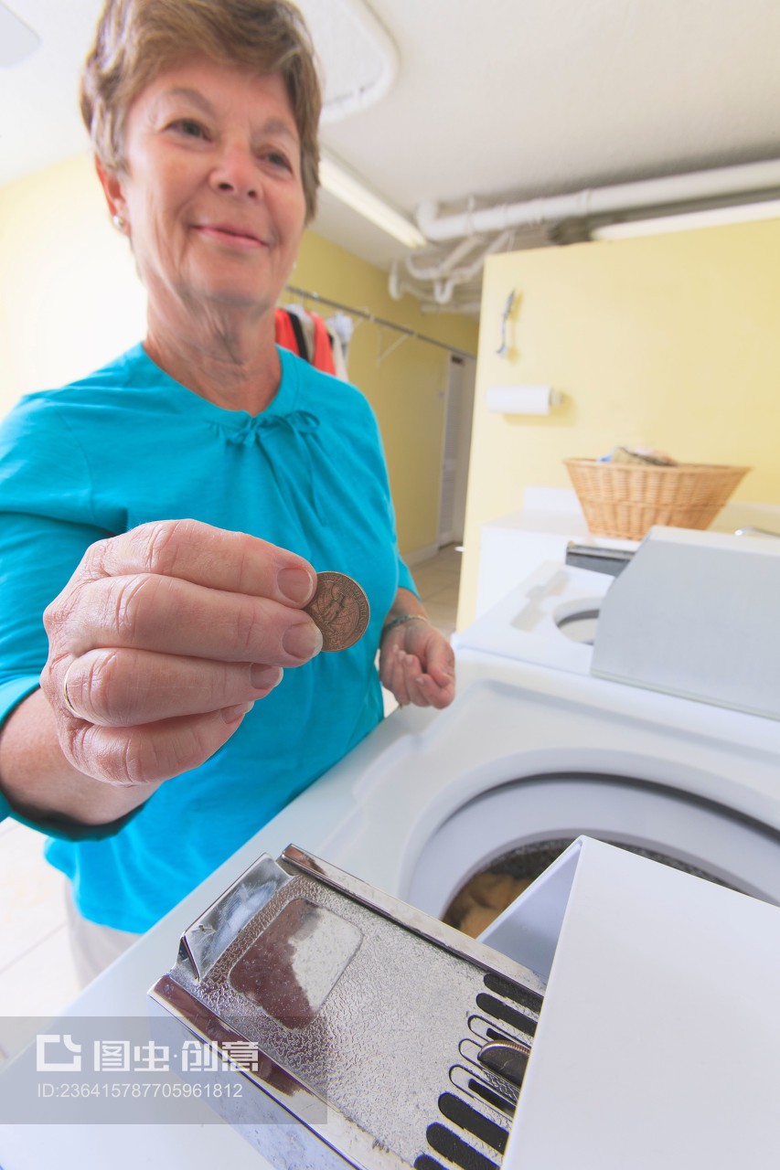 Senior woman putting money into a commercial washing machine